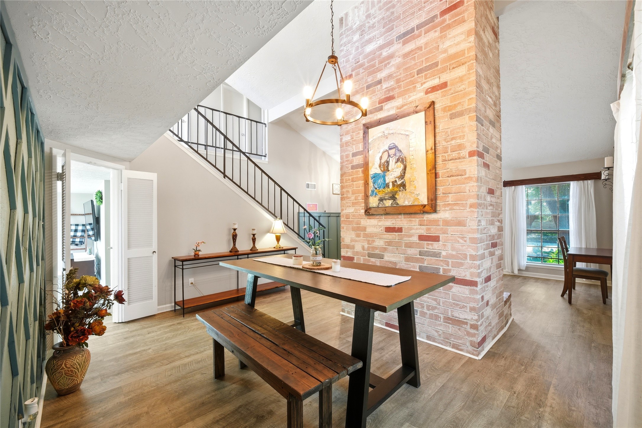 4718 Temple Bell Drive Spring, TX 77388 - Photo 13 of 50 This inviting home features an open dining area with a rustic brick column and a modern light fixture. The space is accented by a stylish accent wall, wooden floors, and a casual dining set. A staircase with a sleek railing adds a contemporary touch, and large windows allow for abundant natural light.