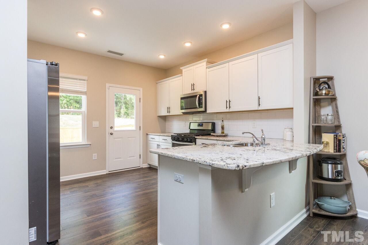 1109 Sandtrap Way Durham, NC 27703 - Photo 11 of 35 a kitchen with stainless steel appliances granite countertop a sink stove and cabinets