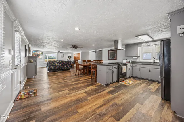 a view of kitchen with kitchen island a sink wooden floor and stainless steel appliances
