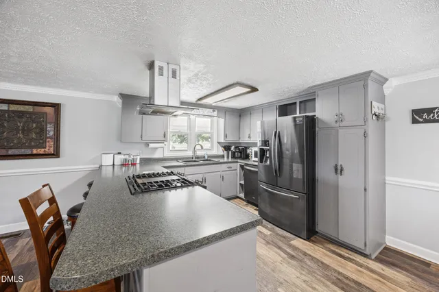 a kitchen with stainless steel appliances granite countertop a refrigerator a stove and white cabinets with wooden floor