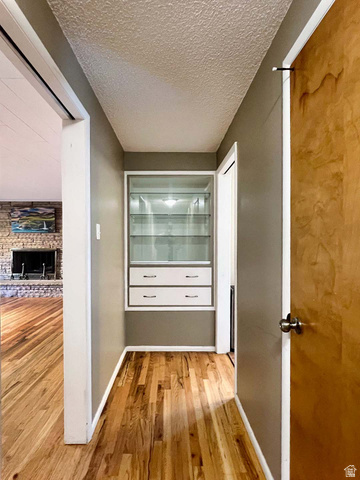 3138 Jean Street Magna, UT 84044 - Photo 13 of 26 Hallway featuring wood-finish flooring, built-in display cabinetry with glass shelving, and integrated drawers