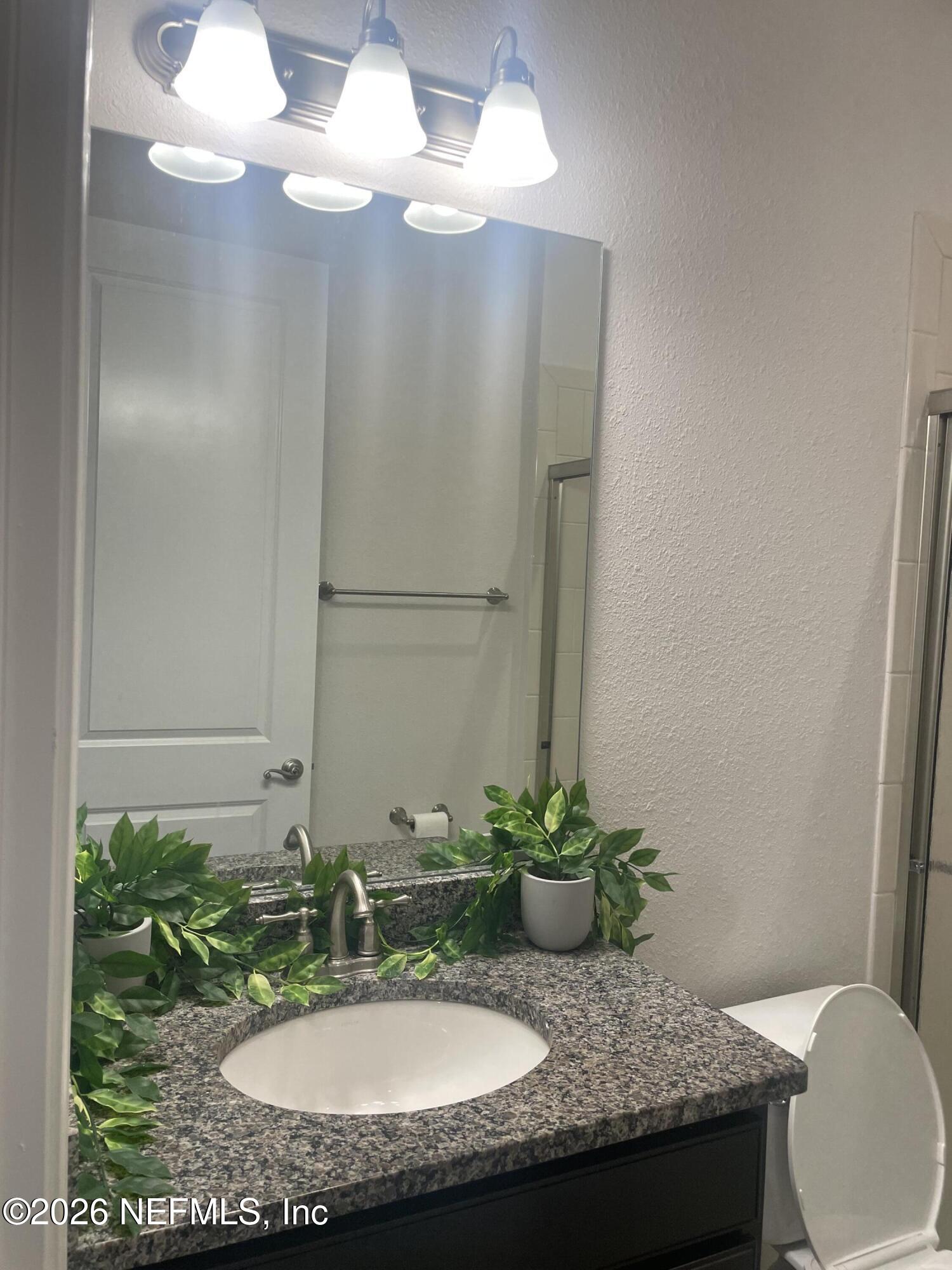 2489 Caprera Circle Jacksonville, FL 32246 - Photo 19 of 23 a bathroom with a granite countertop sink and a mirror