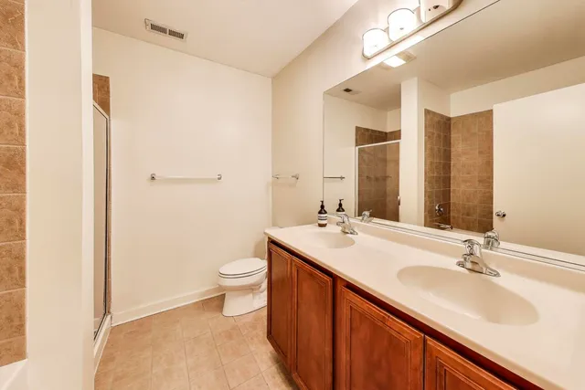 a bathroom with a double vanity sink toilet and mirror