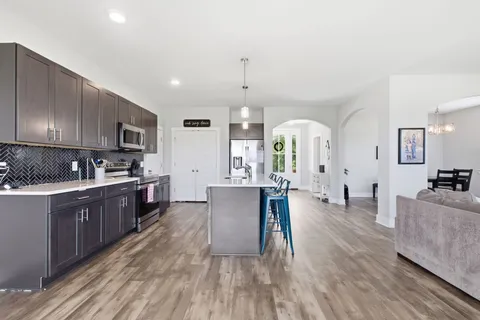 a large kitchen with stainless steel appliances granite countertop a lot of counter space and wooden floors