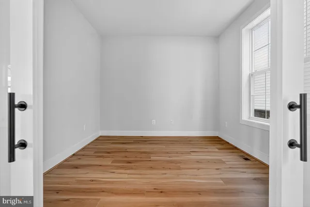 a view of an empty room with wooden floor and a window
