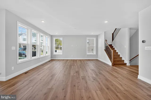 a view of an empty room with wooden floor and windows