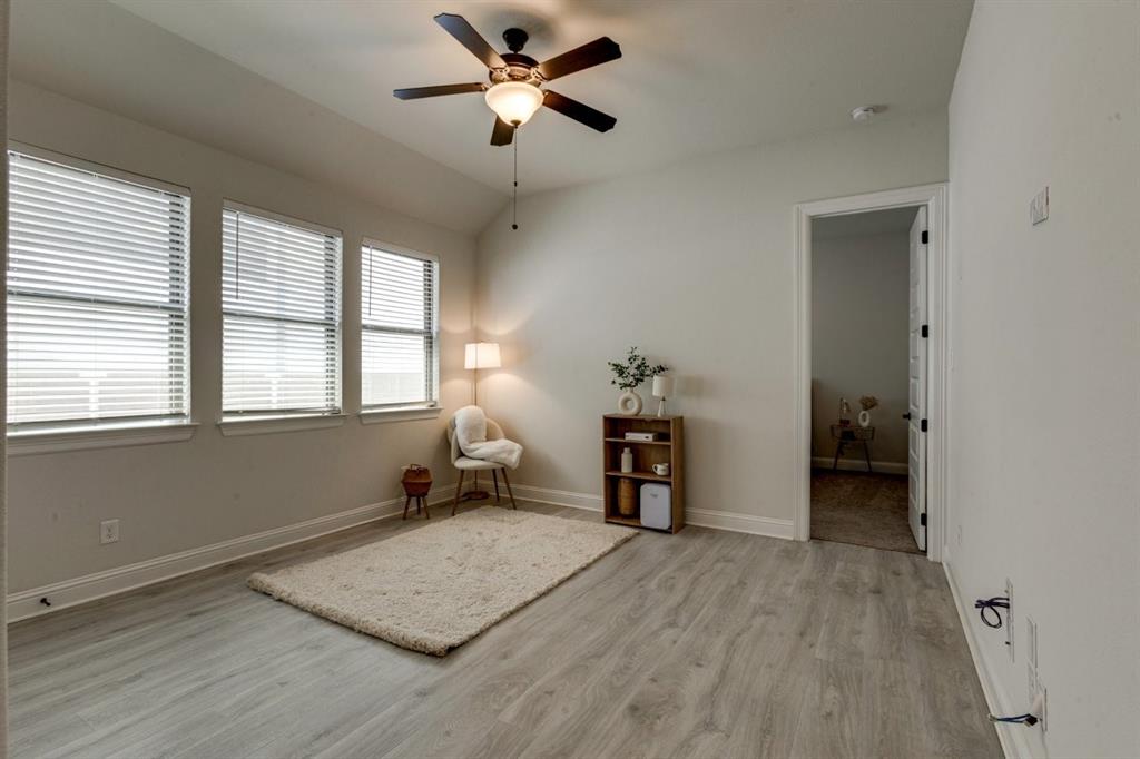 9613 Boulder Pt Road Oak Point, TX 75068 - Photo 22 of 28 Vaulted ceiling room featuring light wood-finish flooring, three large windows with horizontal blinds, a ceiling fan with integrated lighting, and white baseboards