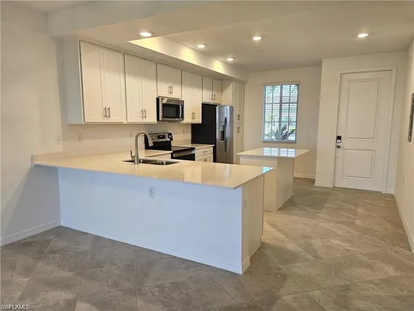 a kitchen with kitchen island granite countertop a sink a counter top space stainless steel appliances and cabinets