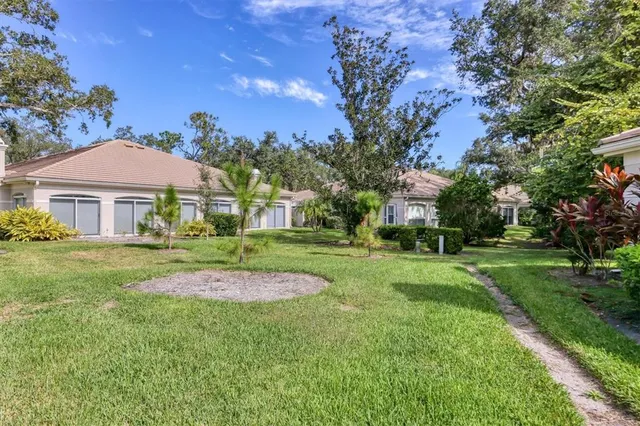 a view of a big house with a big yard plants and large trees