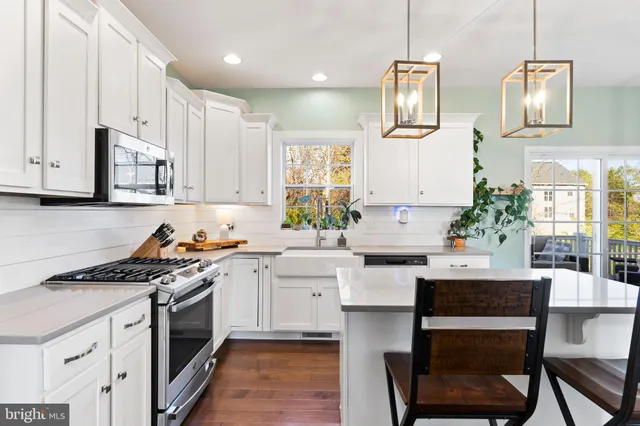 a kitchen with stainless steel appliances a sink a stove a refrigerator cabinets and wooden floor