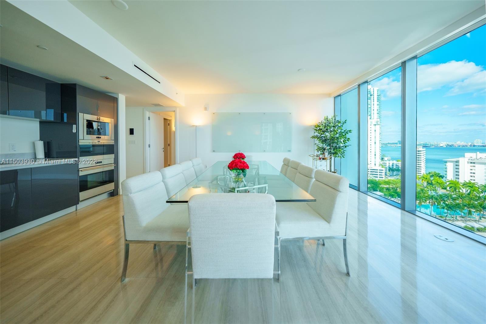 1451 Brickell Avenue, Unit 1803 Miami, FL 33131 - Photo 12 of 35 a dining room with furniture potted plants and wooden floor