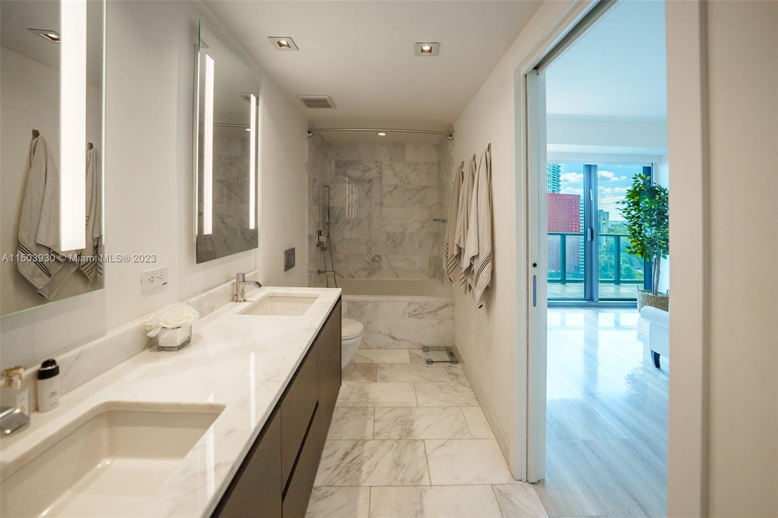 1451 Brickell Avenue, Unit 1803 Miami, FL 33131 - Photo 17 of 35 a bathroom with a tub sink and mirror