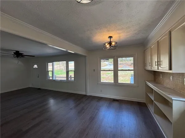 an empty room with wooden floor chandelier and windows