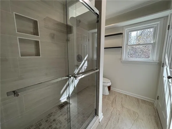 a bathroom with a granite countertop shower a toilet and a sink