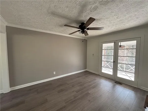 an empty room with wooden floor fan and windows