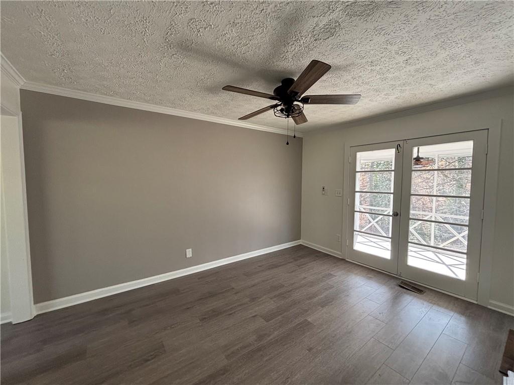 3854 Davis Street Suwanee, GA 30024 - Photo 7 of 24 an empty room with wooden floor fan and windows