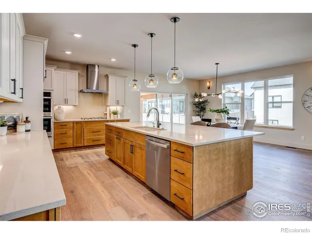 a large kitchen with stainless steel appliances kitchen island granite countertop a large counter top a sink a stove and a wooden floors