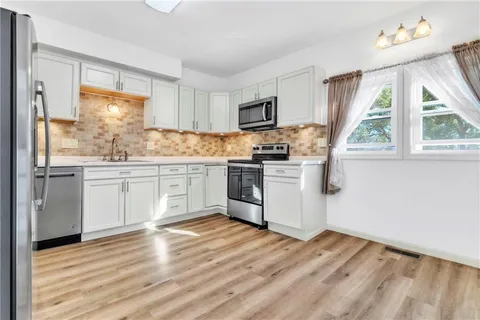 a kitchen with a sink white cabinets and white appliances