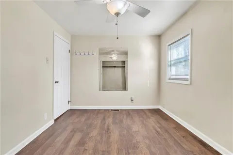 a view of empty room with wooden floor and ceiling fan