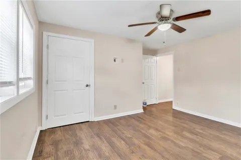 an empty room with wooden floor ceiling fan and windows
