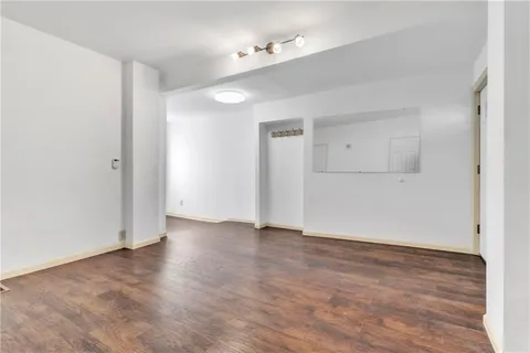 an empty room with wooden floor and a ceiling fan