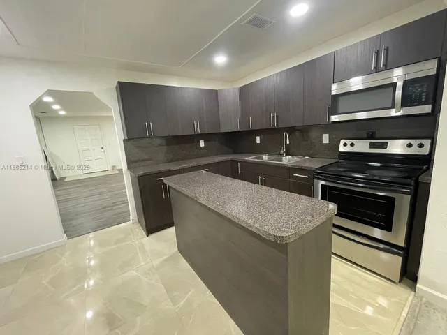 a kitchen with stainless steel appliances a stove a sink and a microwave