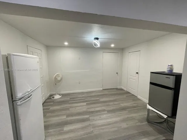a view of a refrigerator in kitchen and an empty room