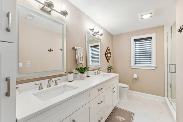 a bathroom with double vanity sink a mirror and a shower