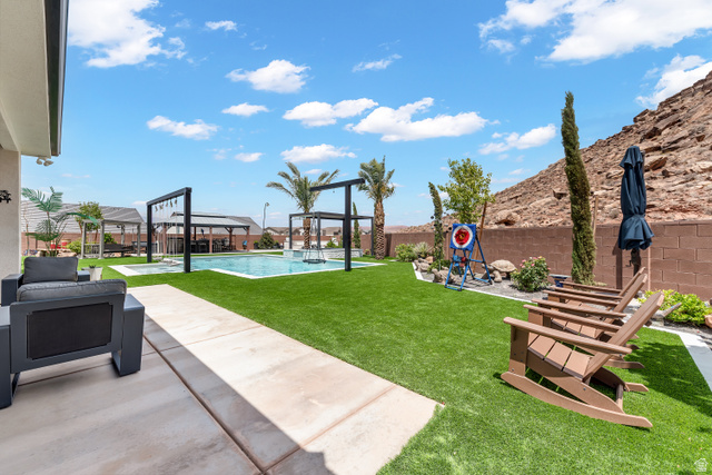 6105 Bunda Way St. George, UT 84790 - Photo 33 of 49 Expansive backyard featuring a central swimming pool with surrounding turf, a concrete patio, and a block wall perimeter