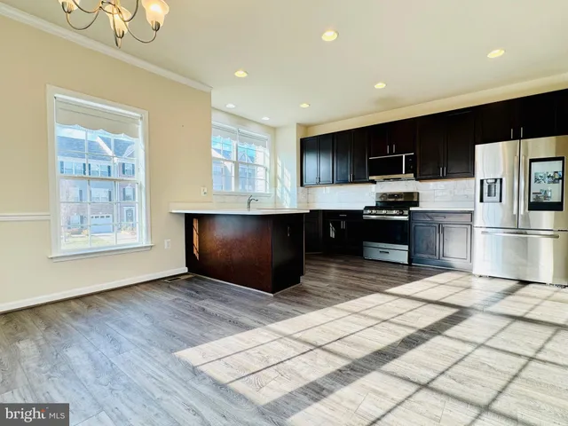 a kitchen with stainless steel appliances kitchen island granite countertop a refrigerator and a sink