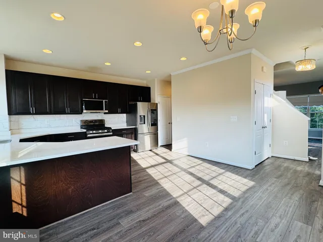 a kitchen with stainless steel appliances granite countertop a sink a stove a refrigerator cabinets and wooden floor