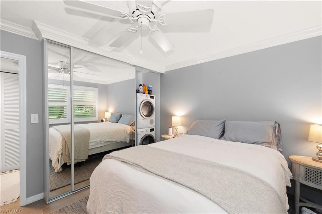 291A 8th Avenue South, Unit 291A Naples, FL 34102 - Photo 19 of 25 Bedroom featuring crown molding, stacked washer and dryer, a ceiling fan, wood finished floors, and closet