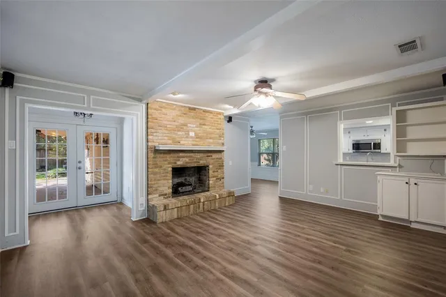 an empty room with wooden floor a fireplace and windows