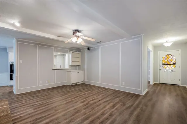 a view of an empty room with window and wooden floor