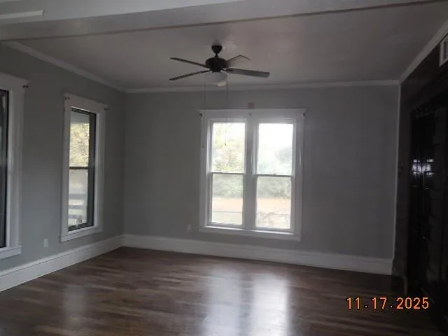 a view of an empty room with wooden floor and a window
