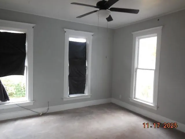 an empty room with a window and a ceiling fan