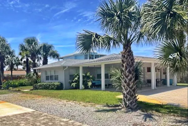 a view of a house with a yard and coconut trees