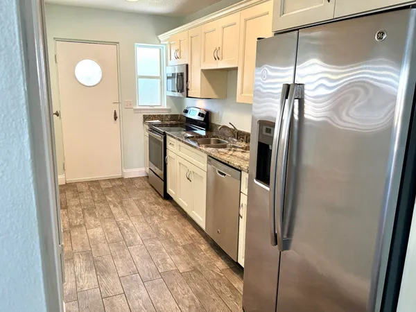 a kitchen with stainless steel appliances granite countertop a refrigerator a stove and a sink