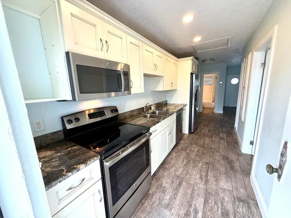 a kitchen with stainless steel appliances granite countertop a stove a sink and a microwave