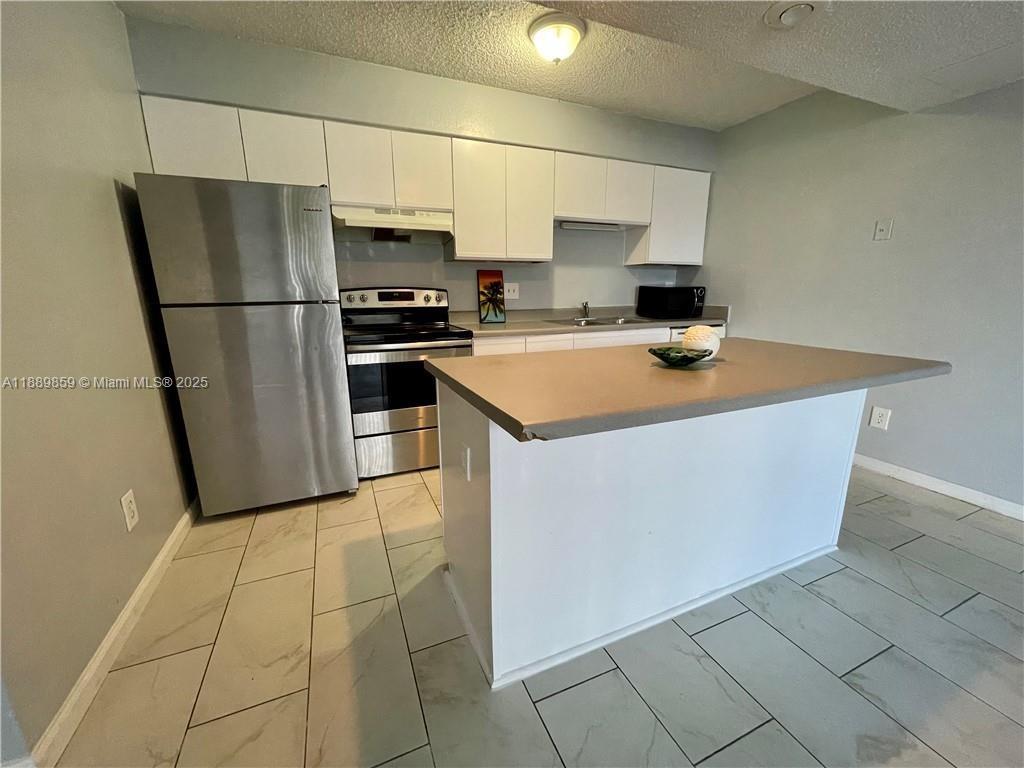 3985 West McNab Road, Unit A101 Pompano Beach, FL 33069 - Photo 1 of 13 a kitchen with stainless steel appliances a refrigerator sink and cabinets