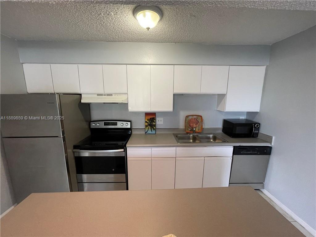 3985 West McNab Road, Unit A101 Pompano Beach, FL 33069 - Photo 2 of 13 a kitchen with a sink a stove a refrigerator and cabinets