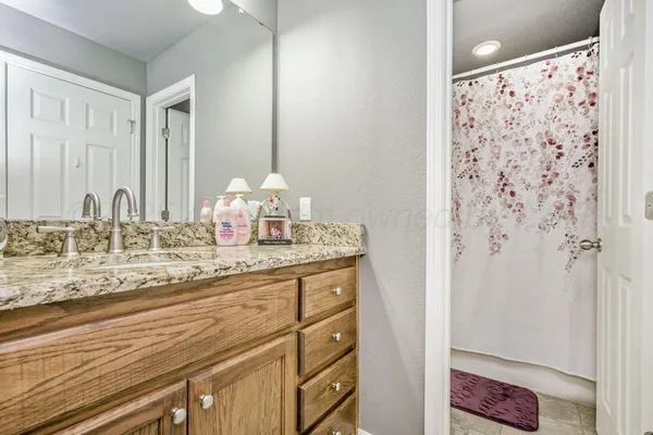 a bathroom with a granite countertop sink a mirror and shower