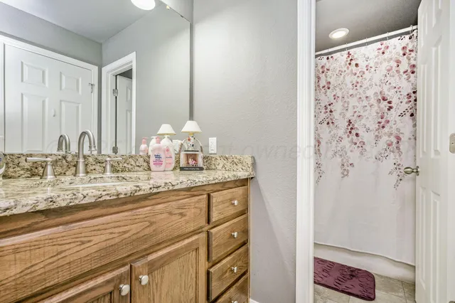 a bathroom with a granite countertop sink a mirror and shower