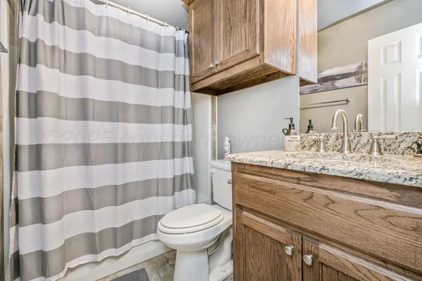 a bathroom with a granite countertop toilet a sink and a mirror