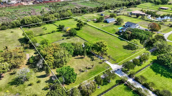 an aerial view of residential houses with outdoor space and trees