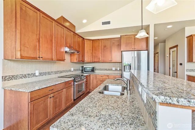 a kitchen with stainless steel appliances granite countertop a stove a sink and a microwave