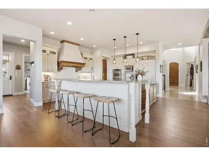 a kitchen with stainless steel appliances kitchen island granite countertop a table chairs refrigerator and a sink