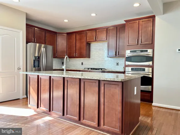 a kitchen with stainless steel appliances granite countertop wooden cabinets a stove top oven a sink and dishwasher with wooden floor