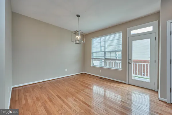 an empty room with chandelier fan and windows