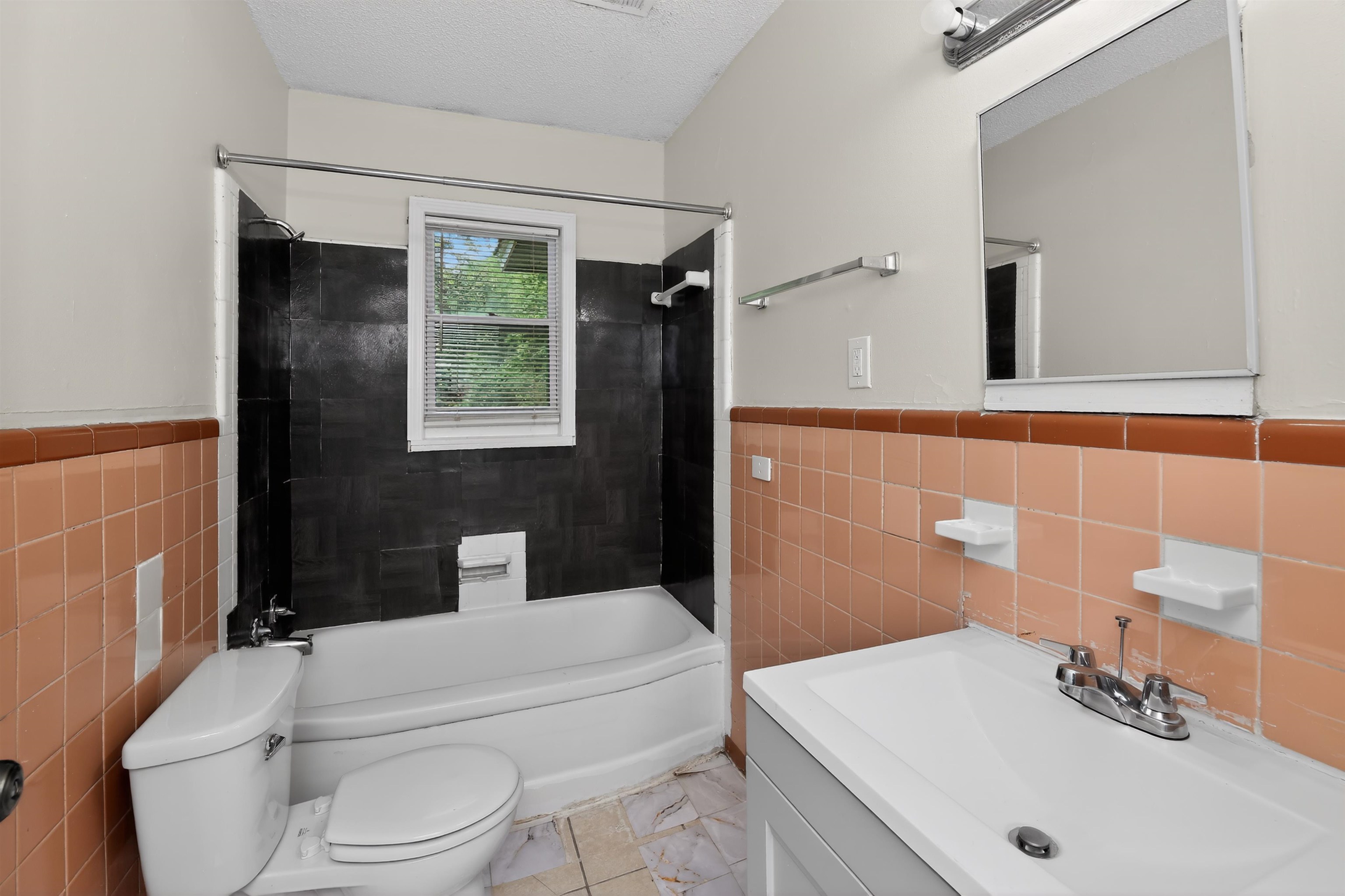 318 East Raines Road Memphis, TN 38109 - Photo 27 of 28 Bathroom featuring a white bathtub, a window with blinds, and white and brown wall tiling